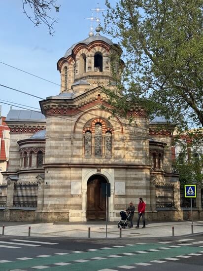 Couple with a stroller walking past St Pantaleon church in Chisinau